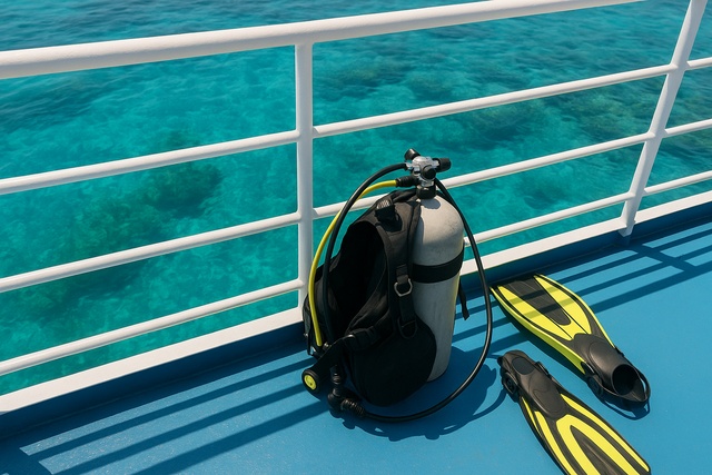 scuba-tank-and-fins-on-boat-deck-over-reef